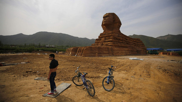 مصر تحتج دولياً على تمثال صيني يشبه "أبو الهول" 1 A man stands next to bicycles in front of a full-scale replica of the Sphinx, part of an unfinished theme park that will also accommodate the production of movies, television shows and animation, on the outskirts of Shijiazhuang