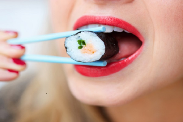 السوشى يزيد جمالك 1 woman eating sushi with chop sticks , close up