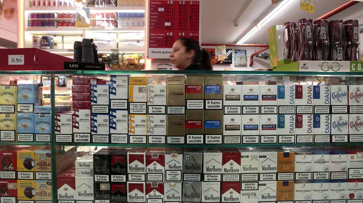 An employee walks past cigarette packets next to an information board which displays the price of cigarettes when purchased in Italy (L) and France (C) with the difference in savings (R), in a supermarket in Latte, near the Franco-Italian border, January 13, 2014. The prices of cigarettes have increased in France on January 13, 2014. REUTERS/Eric Gaillard (ITALY- Tags: BUSINESS