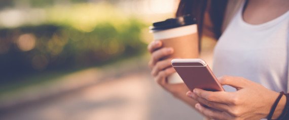Close-up image of woman texting and drinking coffee outdoors