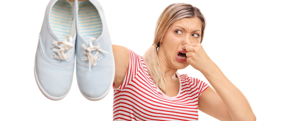 Disgusted woman holding stinky shoes